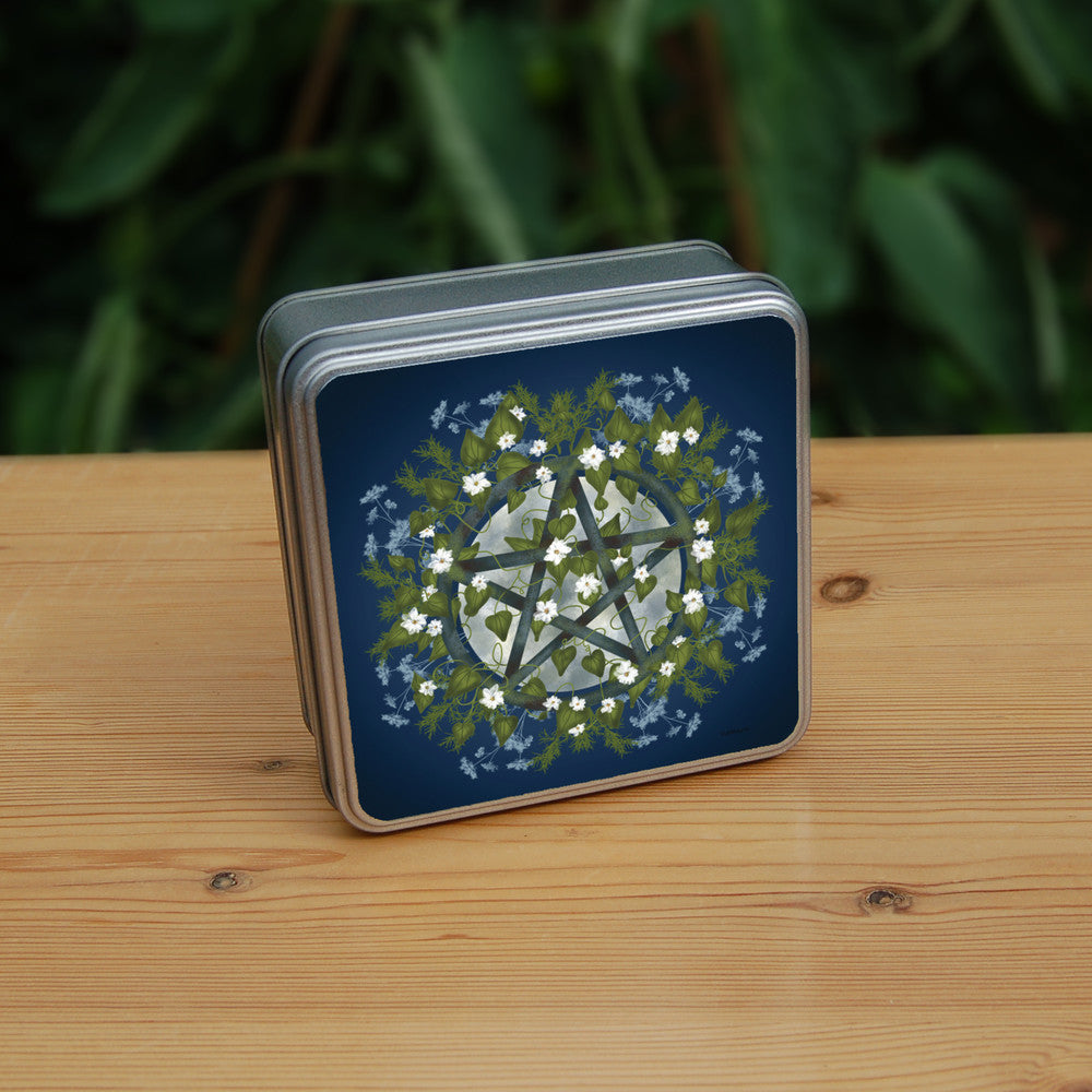 A pentacle symbol overlaid with green leaves, foliage and white flowers which extend outwards towards the edge of the design. A silvery full moon shines behind and within the circle of the pentacle. The background is deep blue.