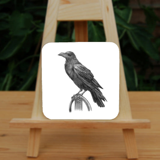 Black and white pencil drawing of a raven sitting on a metal ring.