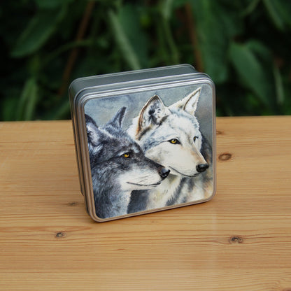 Two grey wolves face to the right, their heads close together. Only the heads of the wolves are shown.