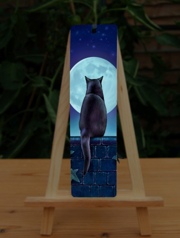 A black cat sitting on a brick wall at night looking towards the full moon. There is ivy on the wall either side of the cat. Colours are mostly deep blues and greens.