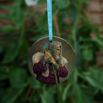 A man with long grey hair and a beard leans on his staff, looking intently to the right. He is wearing a deep purple coat with a pale-coloured fur mantle, and many silver bracelets and rings. A silver pentagram can be glimpsed from behind his staff. The top of the wooden staff has a large, turquoise jewel at the top.