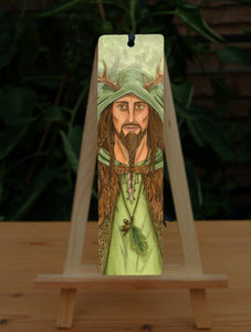 The design features a man in a green cloak with brown fur mantle, long hair and beard in braids, and antlers protruding from his head. He wears a necklace of oak leaf and acorns.