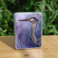 A rectangular tin: A sideways view of the head and neck of a heron. The background is a mottled purple with a swirl pattern.