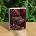 A rectangular tin: A hedgehog shuffles through crisp brown autumn leaves lying on the ground. Woven branches rise upwards, and a leaf falls towards the ground. Colours are browns and reds.