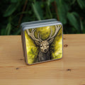 Square metal tin: The head and chest of an antlered stag directly facing the viewer. Oak leaves are drawn to his left and right. The background is mottled yellows and browns.