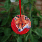 The head of a red fox looking at an angle towards the viewer, coming into the painting from the right. A pale-coloured spiral is coiled on their forehead. The background is red.