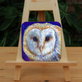 The head of a barn owl, looking directly at the viewer. The background is deep blue.