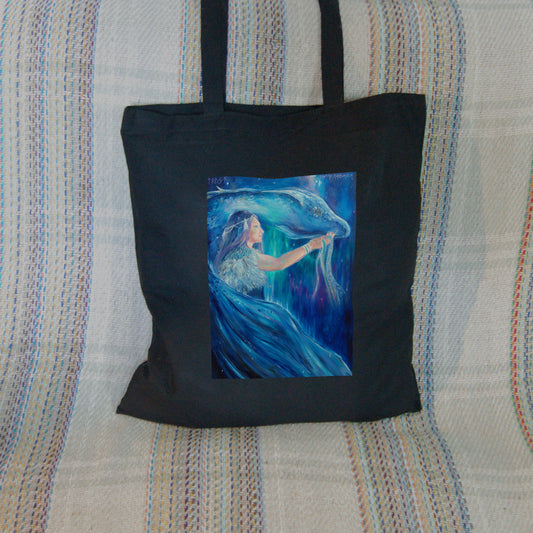 A woman with long blue hair stands in front of a blue dragon. Both look to the right. A wing wraps around one side, with the head on the other. The woman holds what appear to be strands of blue ribbon in her outstretched hand. The overall design colour is blue.