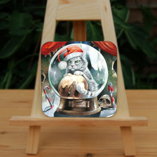 A pale silver tabby cat wearing a santa hat sits in a snow globe, front paws resting on a Christmas pudding. "Krampuss" is written on the globe stand beneath. Candy canes and a skull are pressed into snow around the base of the globe. Behind, red curtains are pulled to the sides to reveal part of a window.