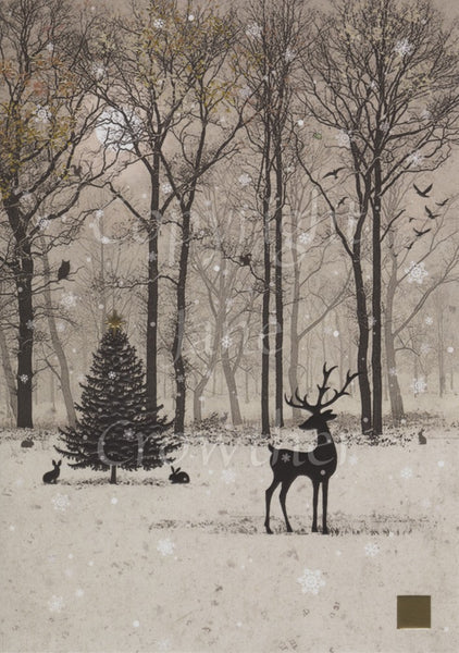 The silhouette of a stag stands in the foreground against a backdrop of bare winter trees. Snow is falling and settling on the ground. A Christmas fir tree stands midway between the trees and stag, a rabbit sits underneath. Colours are mostly browns.