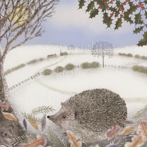 A hedgehog sits in leaves at the bottom of the design. In the background there are snowy fields divided by fences and hedgerows, and in the distance, a row of houses and a church. The snow-covered bare branches of a tree appear at the top left, with berried holly branches on the right. The sky is a wintery blue.