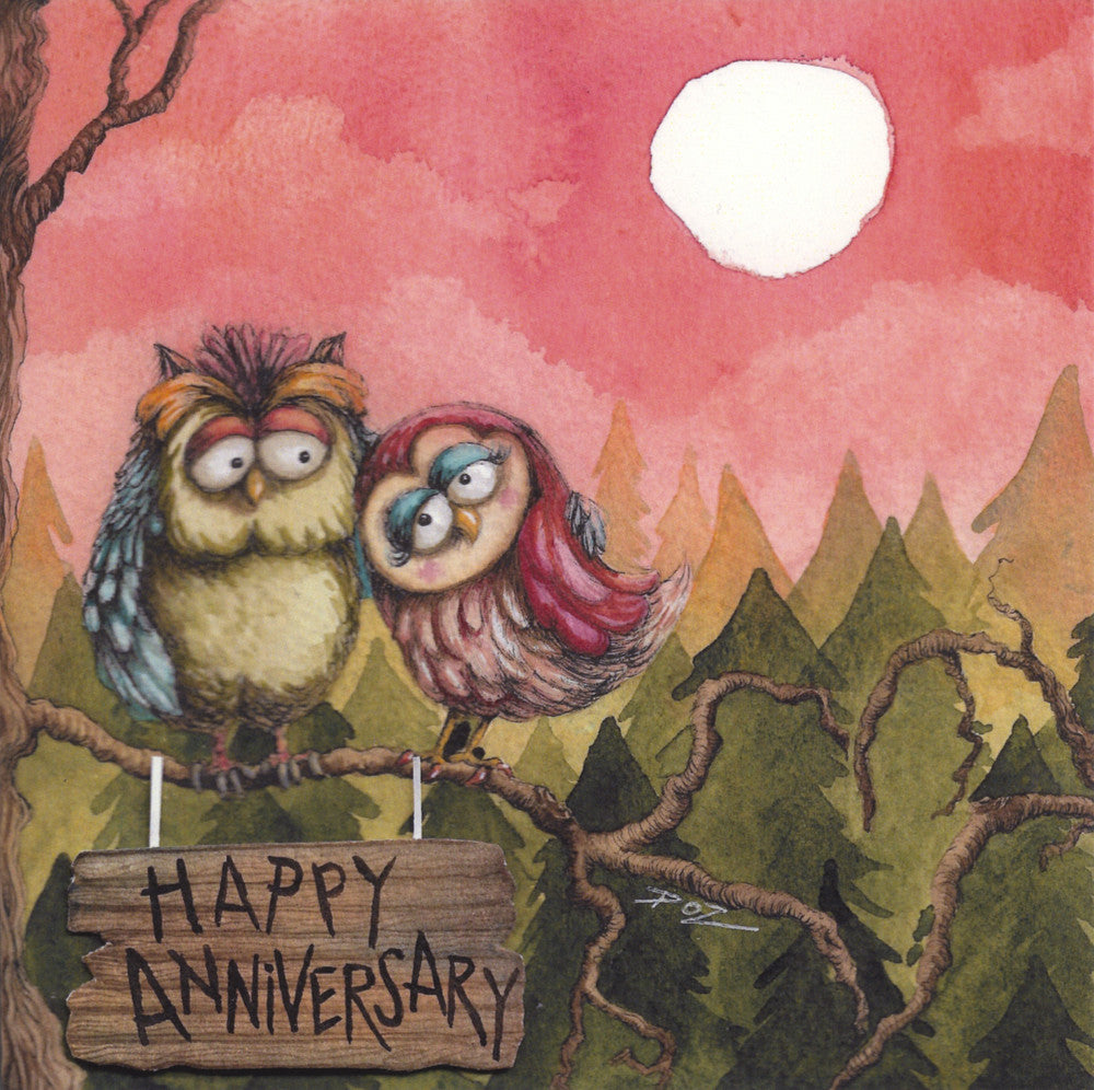 Two colourful owls sit on a crooked branch together. One leans toward the other, eyes in the direction of the second owl. The second owl looks towards the first, wing outstretched to cuddle the first owl. Below them hangs a wooden sign with 'Happy Anniversary' written on it. Behind them stands a green conifer forest, with a deep pink sky and white sun above.