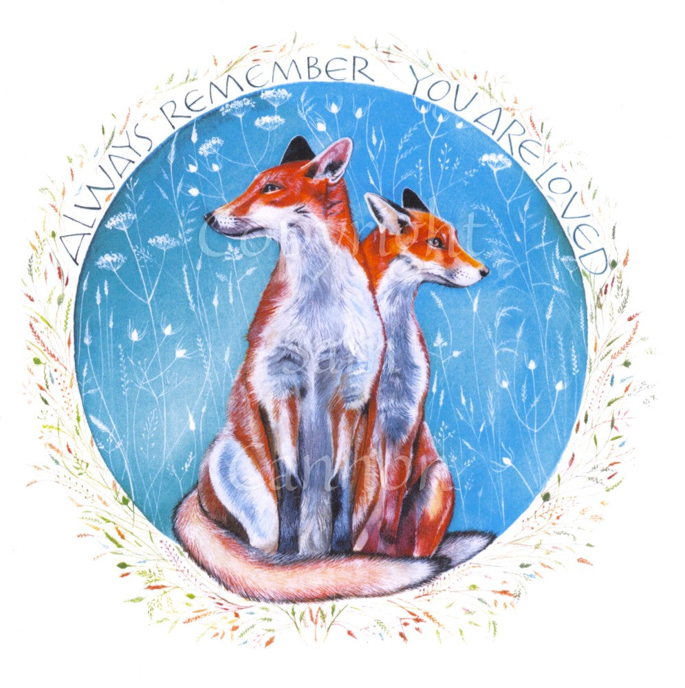 Two red foxes sit together, heads facing away from each other. They're enclosed in a blue circle of white flower and seed heads. The text "Always remember that you are loved" curves round the outer top edge of the circle, together with simple colourful flower and seed heads.