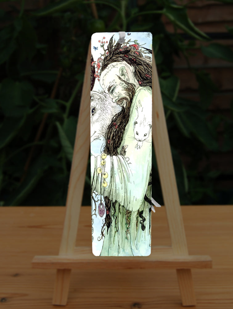 A male figure with long brown hair and beard, both cascading down his body, stands sideways wearing a pale green flowing robe. The side of his head is shaved, and tattooed with a line of characters from the Ogham alphabet. His bound hair contains fungi, a group of feathers, and a mouse. He looks down towards butterflies sitting on his hand. Runes dangle from his arm. A mouse sits in the crook at his elbow. A white stoat appears to form from his shoulder and run down his arm, a badger from his back ...