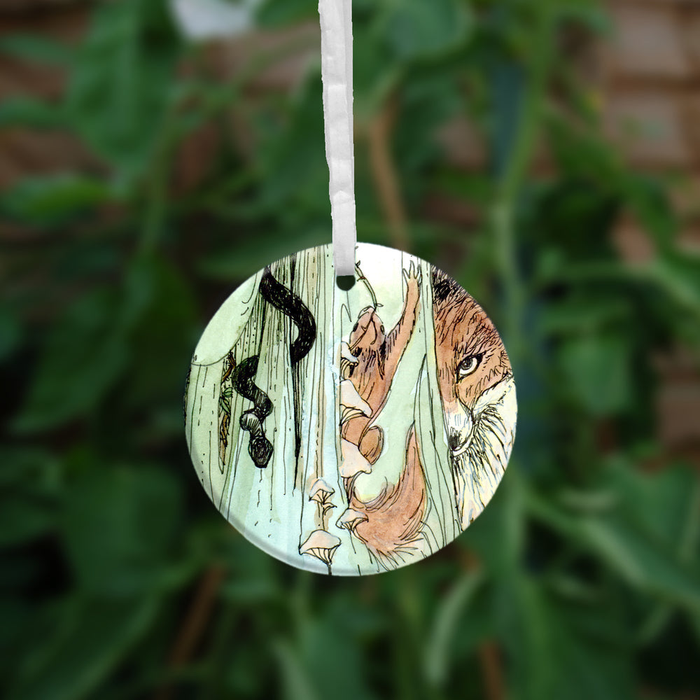 The second side of the ornament. A red fox peers from behind green cloth, a squirrel runs upwards, and a snake winds down.