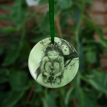 A young child with flowers in their hair crouches next to a branch with a young rooted plant in her cupped hands.