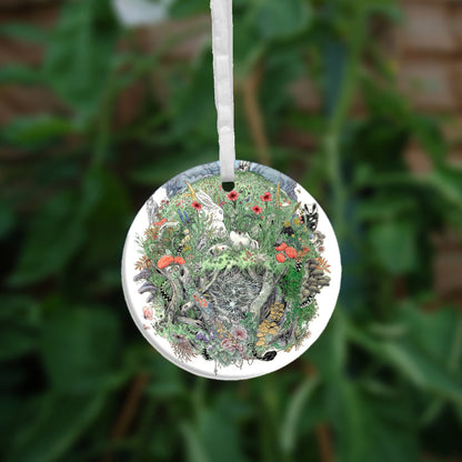 The other side of the ornament. A flower-filled meadow. A stag and badger stand either side, and a hare, blackbird, mouse, and other creatures are nestled within. The head and shoulders of a young woman lying on her back rise from the ground. Beneath her, the bottom half of the oval is a mass of twisting roots, branches, leaves, fungi and toadstools. A snake winds its way through the top half with its head appearing at the bottom.