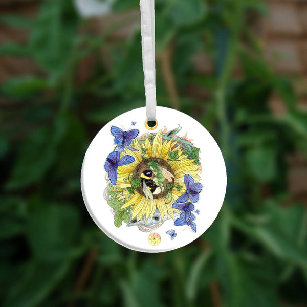 A bee and fairy curl up asleep in the centre of a sunflower. Blue butterflies flutter around them. Ivy and oak twine through the petals. The heads of two dragons can be seen above and below, behind the sunflower. A yellow/orange spiralled disc sits at the top, and similar disc with a star sits at the bottom.