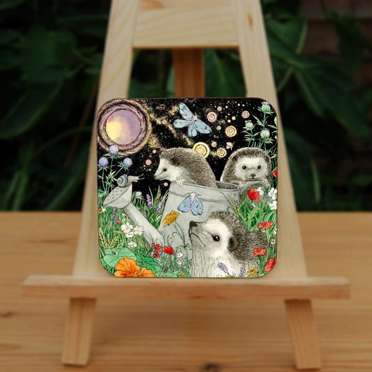 It's night-time and three hedgehogs are playing in a flowerbed. One sits amongst orange and red blooms. Behind him, one is climbing out of a large watering can and another peers over an upturned flower pot. Blue moths sit on the watering can and flitter overhead. A full moon shines in the night sky.