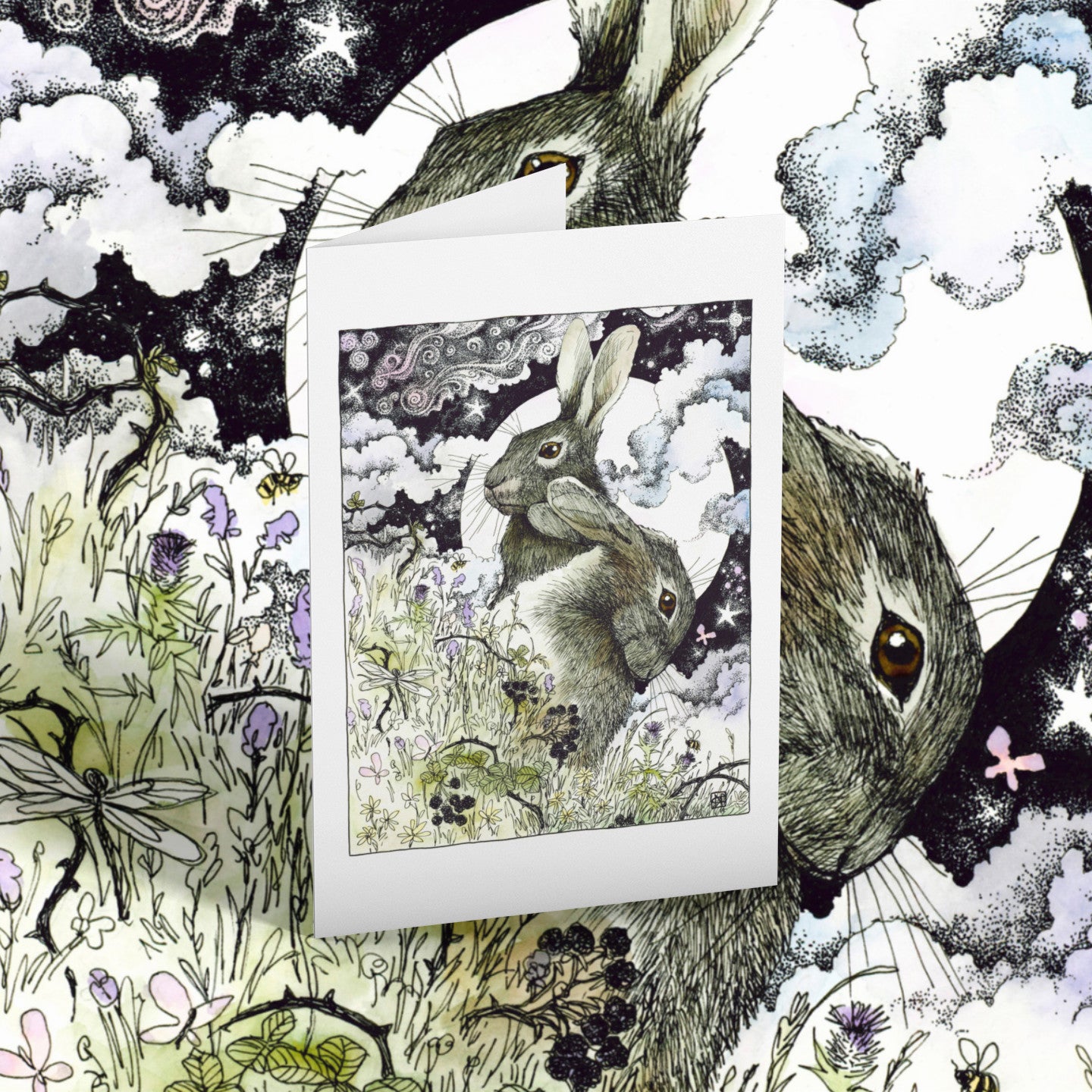 Greeting card of two hares with flowers and butterflies on a matching background.