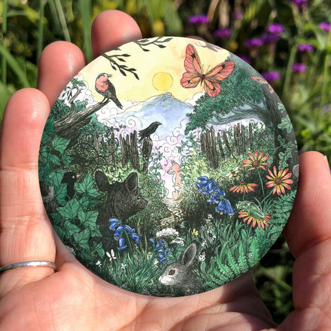 A narrow path leading out of woodland is lined with plants and flowers. Rabbits, hedgehogs and other small creatures are dotted along the path. A fox sits at the far end. Butterflies flit overhead. Birds sing from the branches of a tree. Mountains and a rising sun can be seen in the distance.