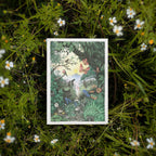 Illustrated card with a forest scene surrounded by greenery and flowers