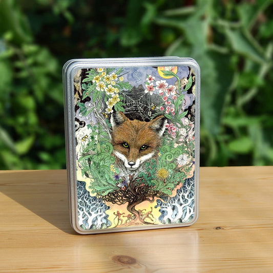 The head of a red fox looks towards the viewer. He's surrounded by a mass of leaves and flowers which rise out from a twisted tree trunk and tangled branches. Figures dance around the base of the tree.