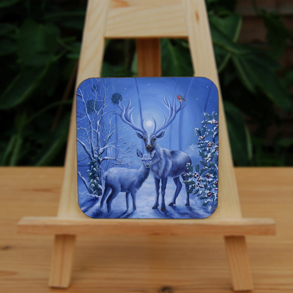 A stag and doe stand facing each other, heads turned towards the viewer. The design is cast in shades of blue. A robin perches on one of the stag's antlers. Snow lies underfoot, and on the branches of the berried holly tree to the right, and bare tree to the left. Pale fairies flit through the branches. Balls of mistletoe sit in the bare tree. A wintery moon rises from between the stag's antlers, and stars can be seen in the sky beyond. 