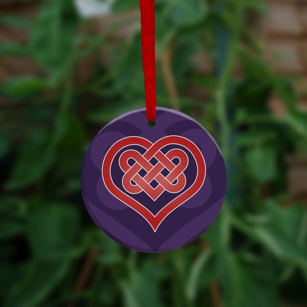 A heart shape which forms into a Celtic knot from the top and into the centre of the heart. The design is red with a white edge. The background is purple.