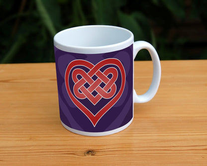 A heart shape which forms into a Celtic knot from the top and into the centre of the heart. The design is red with a white edge. The background is purple.