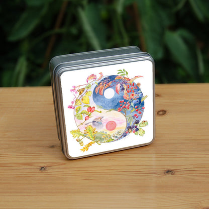 A Yin-Yang shape is surrounded by branches of native trees in autumn colours and some bearing fruit. The left hand half of the shape is filled with a pink/pale orange sky, and a large red sun forms the traditional 'dot' over a grassy hill. Autumn leaves and berries overlay the sky, a jay sings flies over, and fungi sit at the bottom. A moth sits on the outside curve. The right hand half features a dark blue sky with stars, with a white moon forming the 'dot'. Autumn leaves and berries overlay the scene.