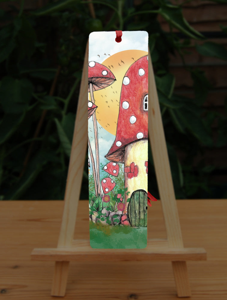 A cream toadstool house with red and white spotted roof, white curved window, and an oval green door at the bottom. An orange sun rises behind the house against a pale cloudy sky, and a flock of birds flies by.