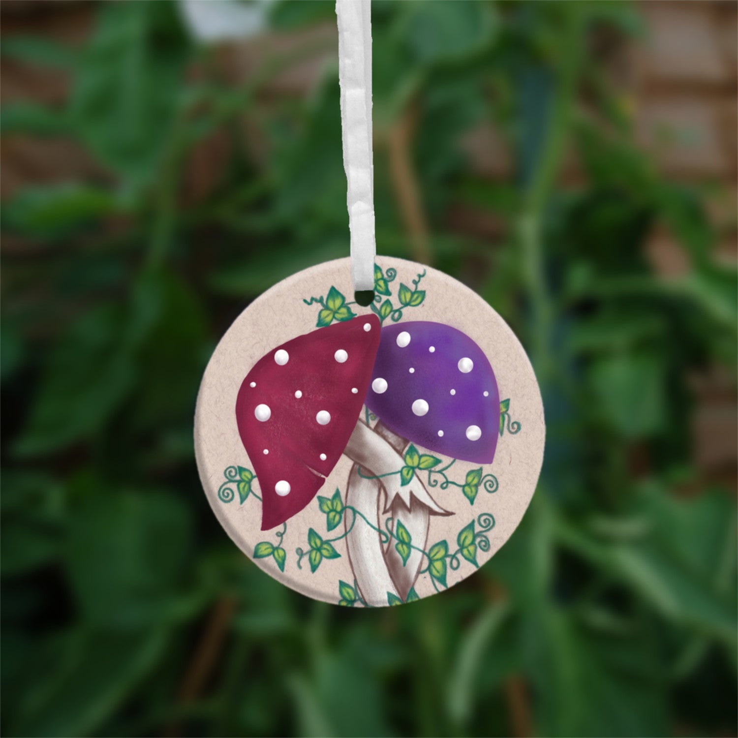 Two toadstools with long pale stems are twined together. The cap of one of them is red with white spots, the other purple with white spots. Leafy green tendrils twine around and up the pair. The background is a mottled beige colour.