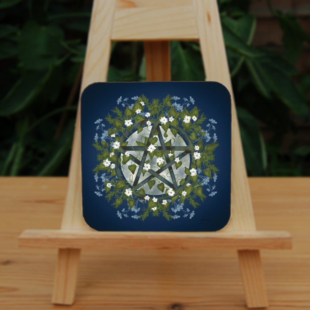A pentacle symbol overlaid with green leaves, foliage and white flowers which extend outwards towards the edge of the design. A silvery full moon shines behind and within the circle of the pentacle. The background is deep blue.